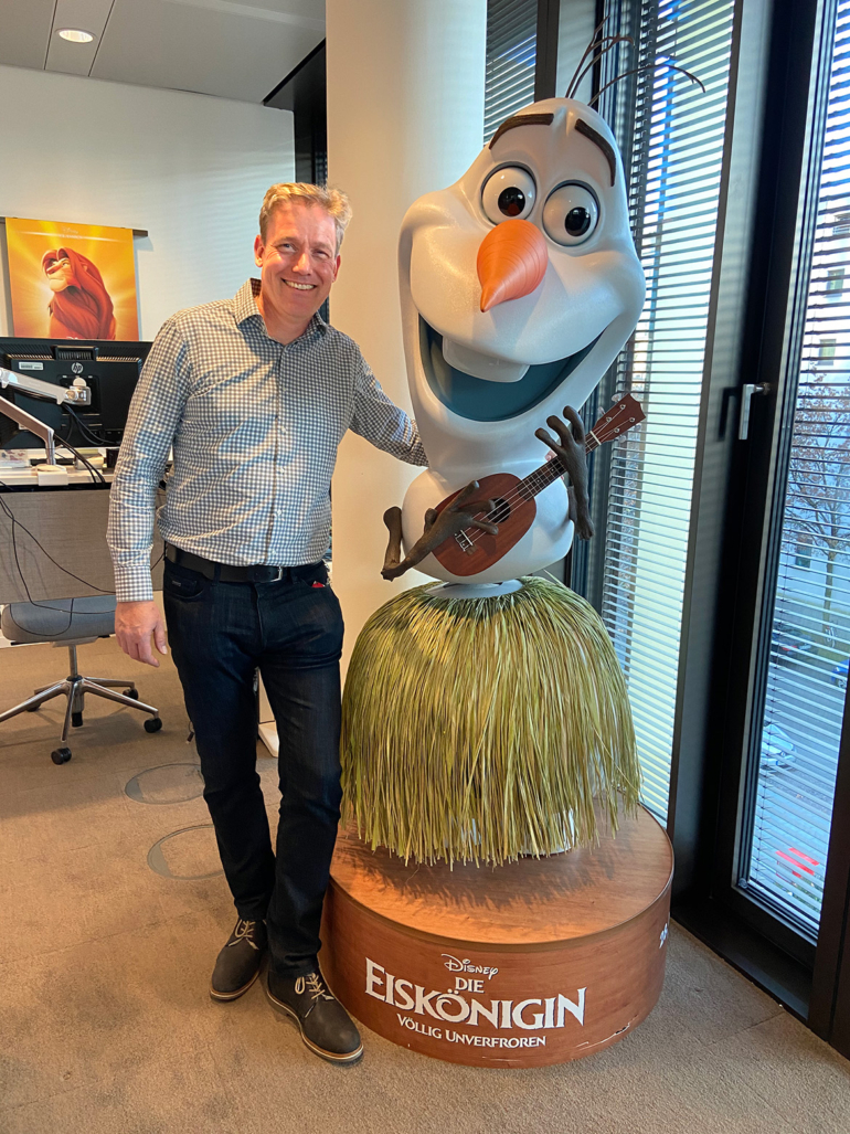 Oliver Jackson und eine Figur von Olaf Doll: Das Ende einer Ära bei Disney Oliver Jackson verabschiedet sich von seinem Arbeitsplatz bei Disney und posiert neben einer fröhlichen, mannshohen Figur von Olaf Doll.