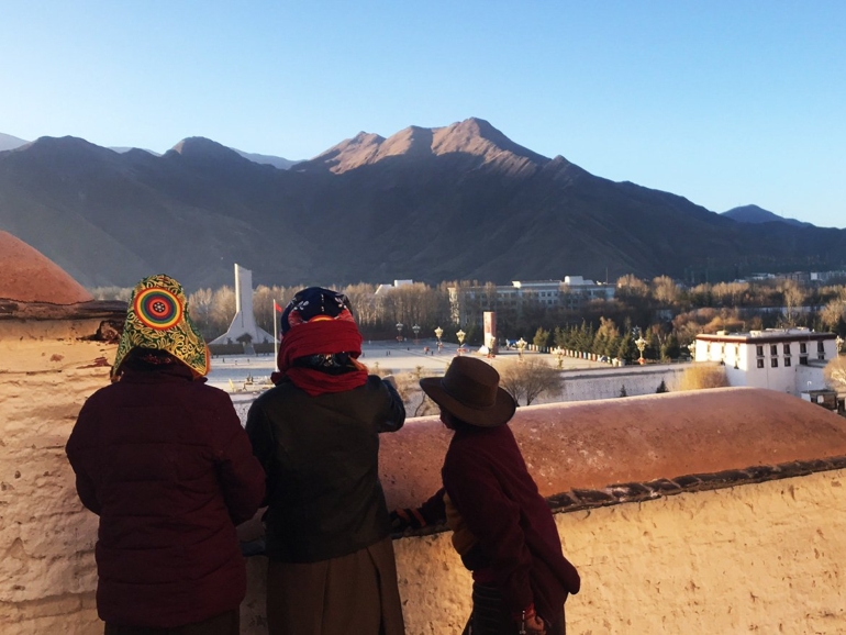 Stille Wächter: Die Berge von Lhasa Drei Personen betrachten ehrfurchtsvoll die majestätischen Berge Tibets, die sich sie sich über Lhasa erheben.