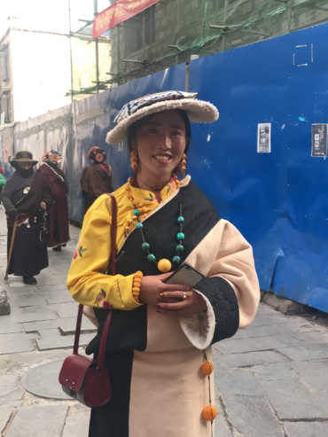 Tradition trifft Moderne: Stil einer jungen Tibeterin Eine stilvolle junge tibetische Frau in farbenfroher, traditioneller Kleidung und Schmuck bei einem Fest in Lhasa.