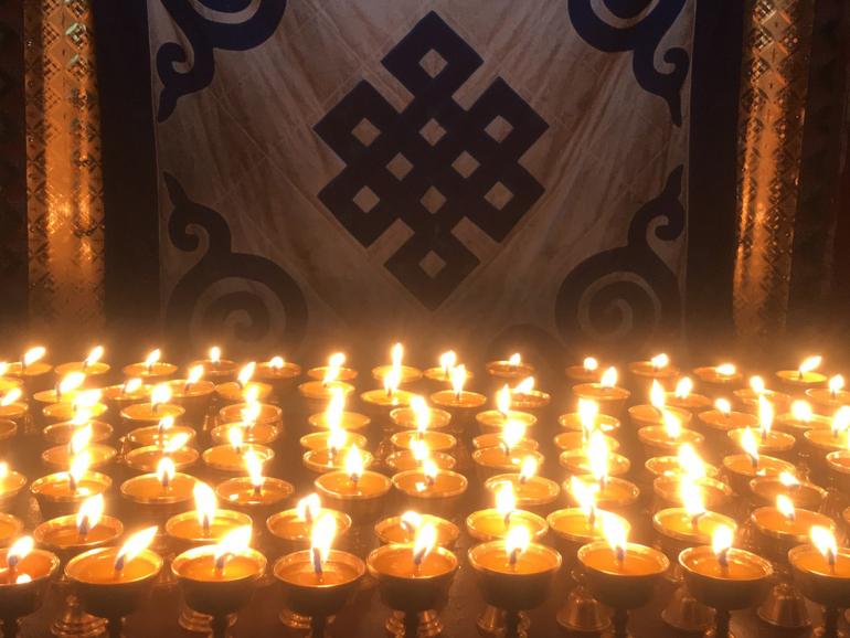 Symbolische Beleuchtung: Der Endlose Knoten und Butterlampen in Lhasa Spirituelles Leuchten von Butterlampen, die in einem buddhistischen Tempel in Lhasa als Zeichen der Hingabe entzündet wurden, vor einem traditionellen Endlosen Knoten.
