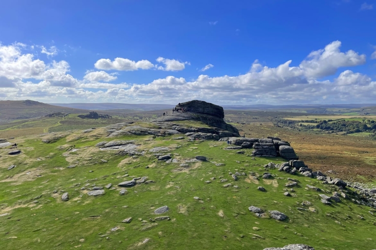 Monumente der Natur: Haytor Rocks im Herzen des Dartmoor Die Haytor Rocks im Dartmoor National Park, Devon, an einem sonnigen Tag mit Wanderern, die die Landschaft genießen.