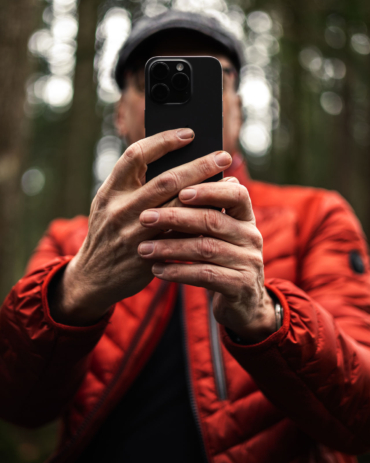 Elmar im Wald - Farbenspiel und Ausdruckskraft Porträtfotografie von Elmar im Wald mit roter Jacke und Smartphone, fotografiert von Viktoria Jäger.
